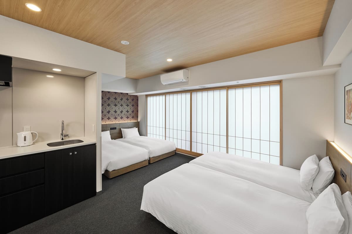 A hotel room with two beds, a sink, and a large window with a view.