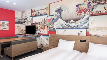 A hotel room with a bed, a TV, and a wall decorated with Japanese art.
