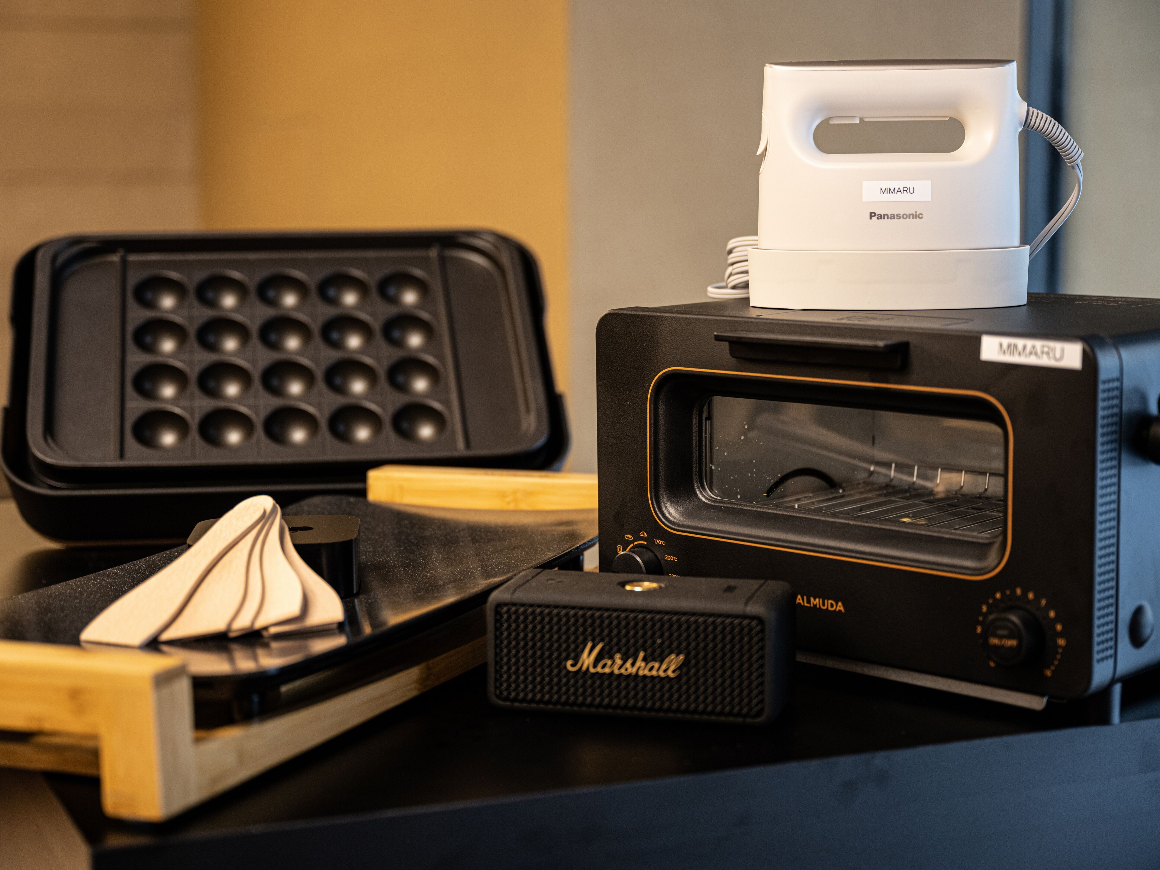 A kitchen with a waffle maker, a toaster, and a Marshall speaker.