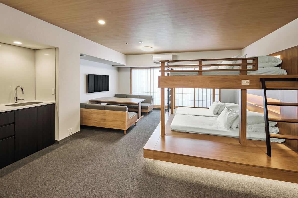 A modern, compact room with bunk beds, a sofa, a small table, and a built-in sink.