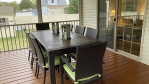 A covered patio with a table and chairs, a view of the backyard, and a sliding glass door leading to an interior space. - Family fun! Beach, Kayaking, yard games, large fenced yard, fire pit. 2 mi beach (Ocean View)