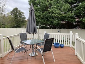 Eine Terrasse mit einem Tisch mit Glasplatte und vier Stühlen, umgeben von einem weißen Geländer.