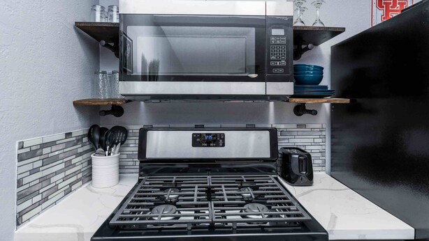 A compact kitchen with a microwave, toaster, and gas stove.