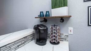 A kitchen area with a coffee maker, a mug rack, and a planter on the wall.