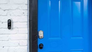 A blue door with a keypad lock and a traditional keyhole, adjacent to a white brick wall.
