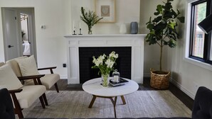 A living room with a fireplace, a round coffee table, and a large plant. - Family Style Cottage 5 minutes from the Gaslight District  (North dumfries)