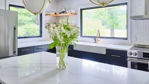 A modern kitchen with a marble countertop, stainless steel appliances, and a large window with a view of greenery. - Family Style Cottage 5 minutes from the Gaslight District  (North dumfries)