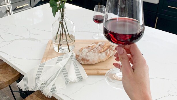 A kitchen with a marble countertop, a loaf of bread, a vase with flowers, and a glass of red wine. - Family Style Cottage 5 minutes from the Gaslight District  (North dumfries)
