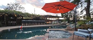 Ein Poolbereich mit Liegestühlen, einer Bar und einem Sonnenschirm.