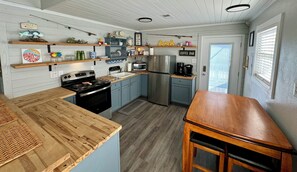 Compact kitchen with modern layout, gas stove, refrigerator, and microwave, featuring a small island with sink and ample workspace.