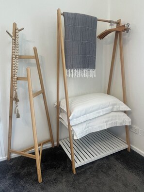 A wooden ladder with a hanging beaded ornament, a bench with a grey cloth, and a white pillow.