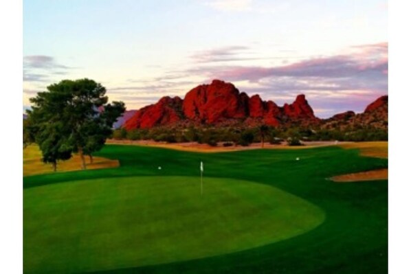 A golf course with a flagstick, trees, and red rock formations in the background. - Walk to Old Town, Heated Pool, Fast Internet,  Continental Breakfast included.  (Scottsdale)