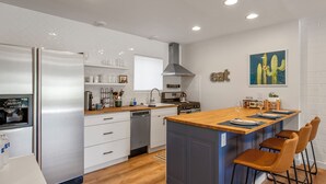 A modern kitchen with a central island, stainless steel appliances, and a dining area with bar stools. - Walk to Old Town, Heated Pool, Fast Internet,  Continental Breakfast included.  (Scottsdale)