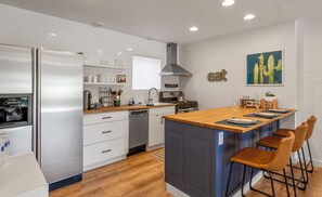 A modern kitchen with a central island, stainless steel appliances, and a dining area with bar stools. - Walk to Old Town, Heated Pool, Fast Internet,  Continental Breakfast included.  (Scottsdale)