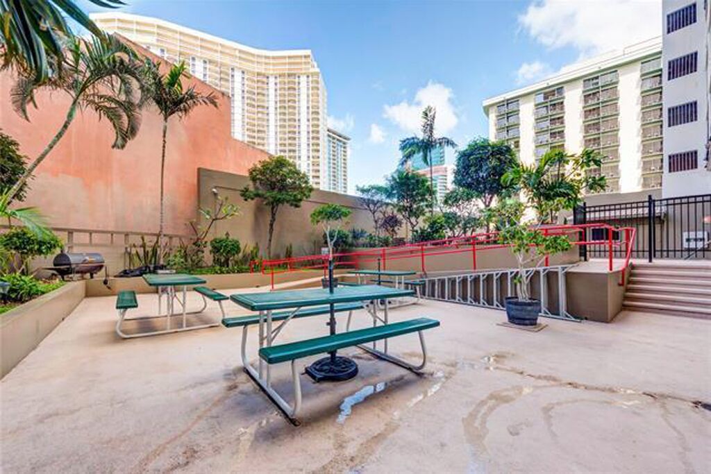 An outdoor patio area with picnic tables and a barbecue grill.