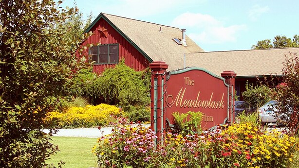 Un edificio de estilo granero rojo con un letrero que dice The Meadowlark Inn.