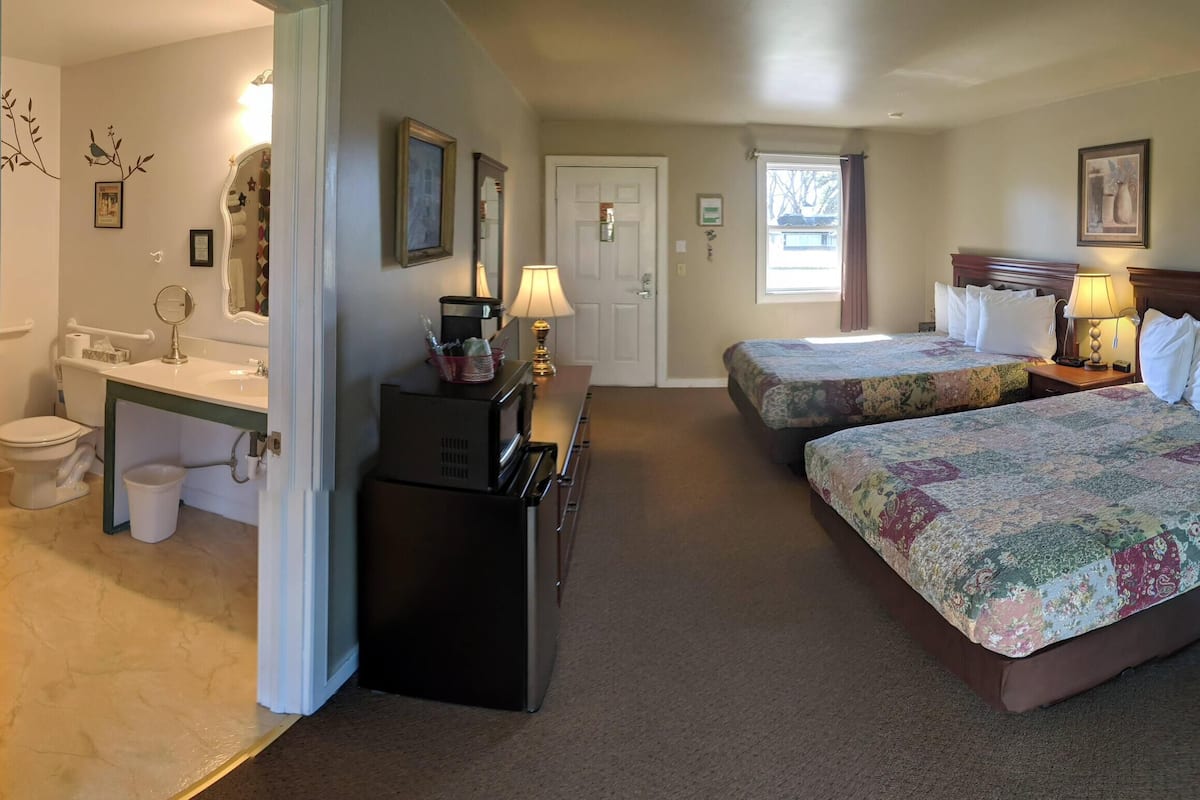 Une chambre d’hôtel avec deux lits, une salle de bain, un bureau et une table à manger.