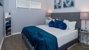 Un dormitorio con cama, ventilador de techo, mesita de noche y decoración en la pared.