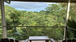 A covered outdoor seating area with a table and chairs, overlooking a lush green landscape. - Chauffeur & Concierge included Luxury Jungle/Beach Pool @ Villa Tiquicia (Quepos)