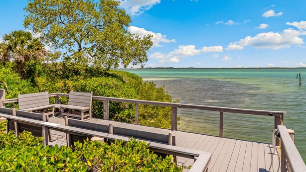 A wooden deck with benches overlooking turquoise waters, surrounded by lush greenery. - Private townhome steps from the beach and right next to the pool (Longboat Key)