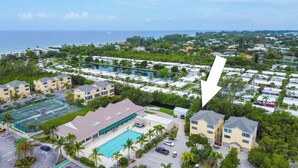 An aerial view of a coastal resort with multiple buildings, a swimming pool, and a tennis court. - Private townhome steps from the beach and right next to the pool (Longboat Key)