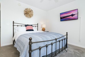 Una cama bien hecha con un edredón estampado, un televisor montado en la pared y un adorno decorativo.