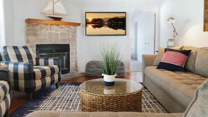 Una sala de estar con chimenea de piedra, un sofá, un sillón y una mesa de centro con una planta.