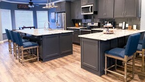 A modern kitchen with dark cabinetry, a central island, and bar stools.