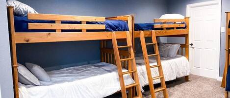 A bunk bed room with a ceiling fan, a door, and a carpeted floor.