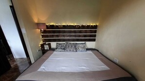 Un letto con testiera, un comodino e una lampada.