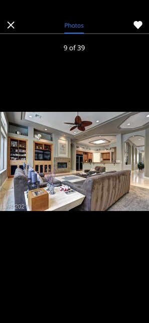 A spacious living room with a large sofa, a coffee table, and a ceiling fan.