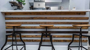 Una zona de cocina con barra de madera y tres taburetes.