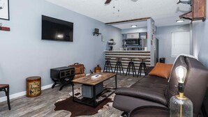 Una sala de estar moderna con un sofá de cuero, una mesa de centro y un televisor montado en la pared.