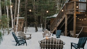 Une cabane en bois dotée d’une terrasse, d’un espace salon extérieur et d’un foyer.