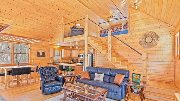 Une cabane en bois spacieuse, dotée d’une chambre à coucher en mezzanine, d’un coin repas et d’une cuisine.