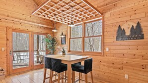 Un intérieur en bois avec une grande fenêtre, une table et deux chaises.