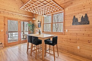 A wooden interior with a large window, a table, and two chairs.