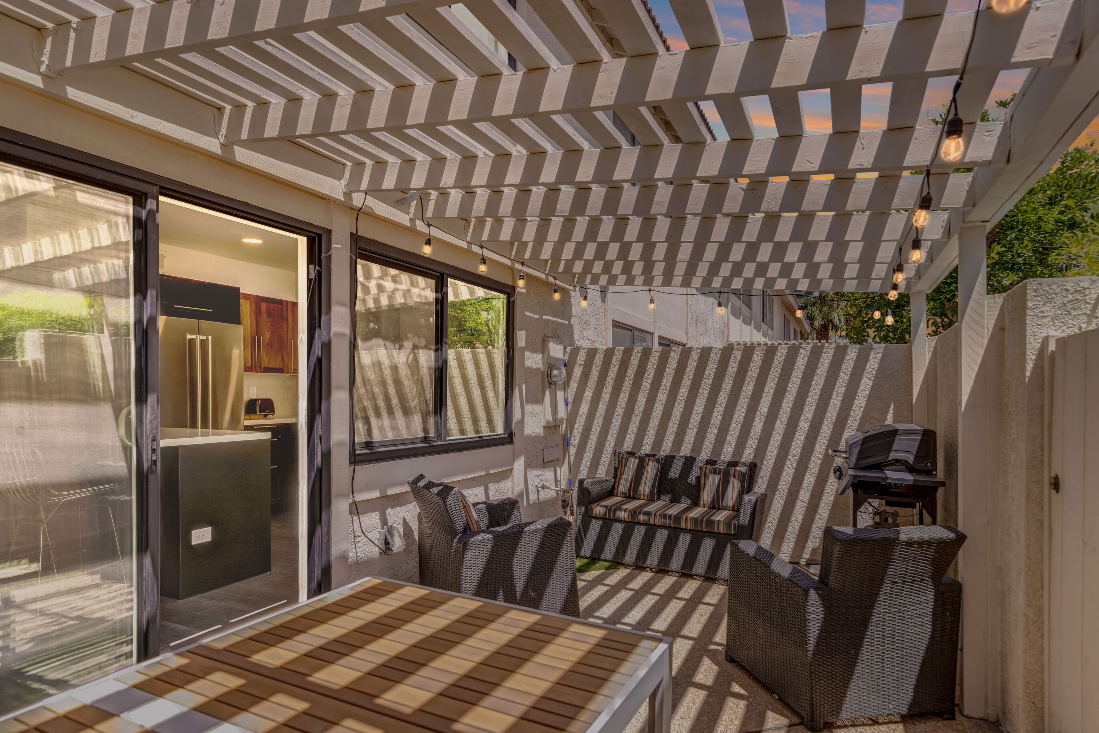 Une terrasse extérieure dotée d’une pergola, d’un espace salon et d’un barbecue.