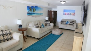 A living room with two sofas, a coffee table, a TV, and artwork on the walls.