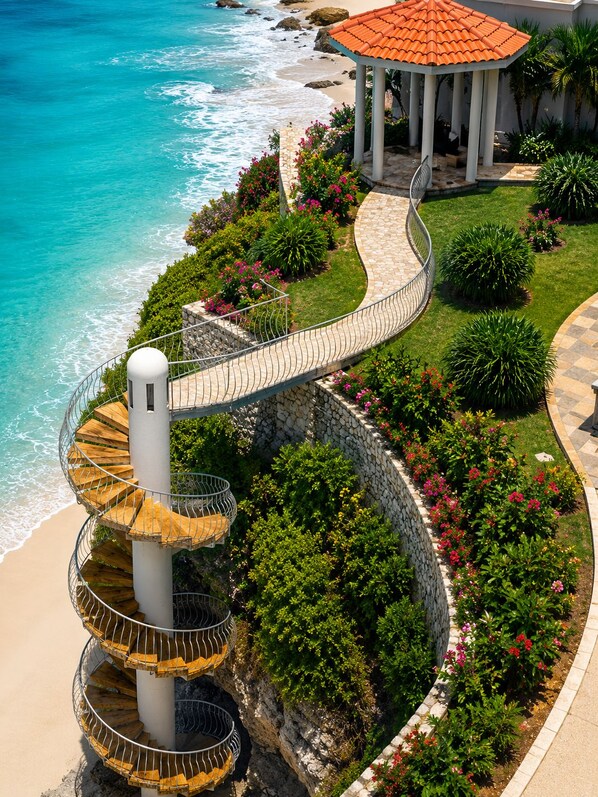 A spiral staircase leading to a beach area with a gazebo.