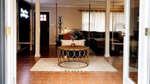 A well-lit entrance with a 'WELCOME' mat, a round metal table with a woven top, and a dark-colored sofa in the background. - Gentry Pines: Huge backyard ~ Loaded Game Room (Vestavia Hills)