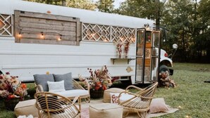 A white RV with a cozy outdoor seating area featuring wicker chairs, a small sofa, and a table. - Gentry Pines: Huge backyard ~ Loaded Game Room (Vestavia Hills)