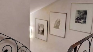 Eine Treppe mit Metallgeländer und drei gerahmten Bildern an der Wand.