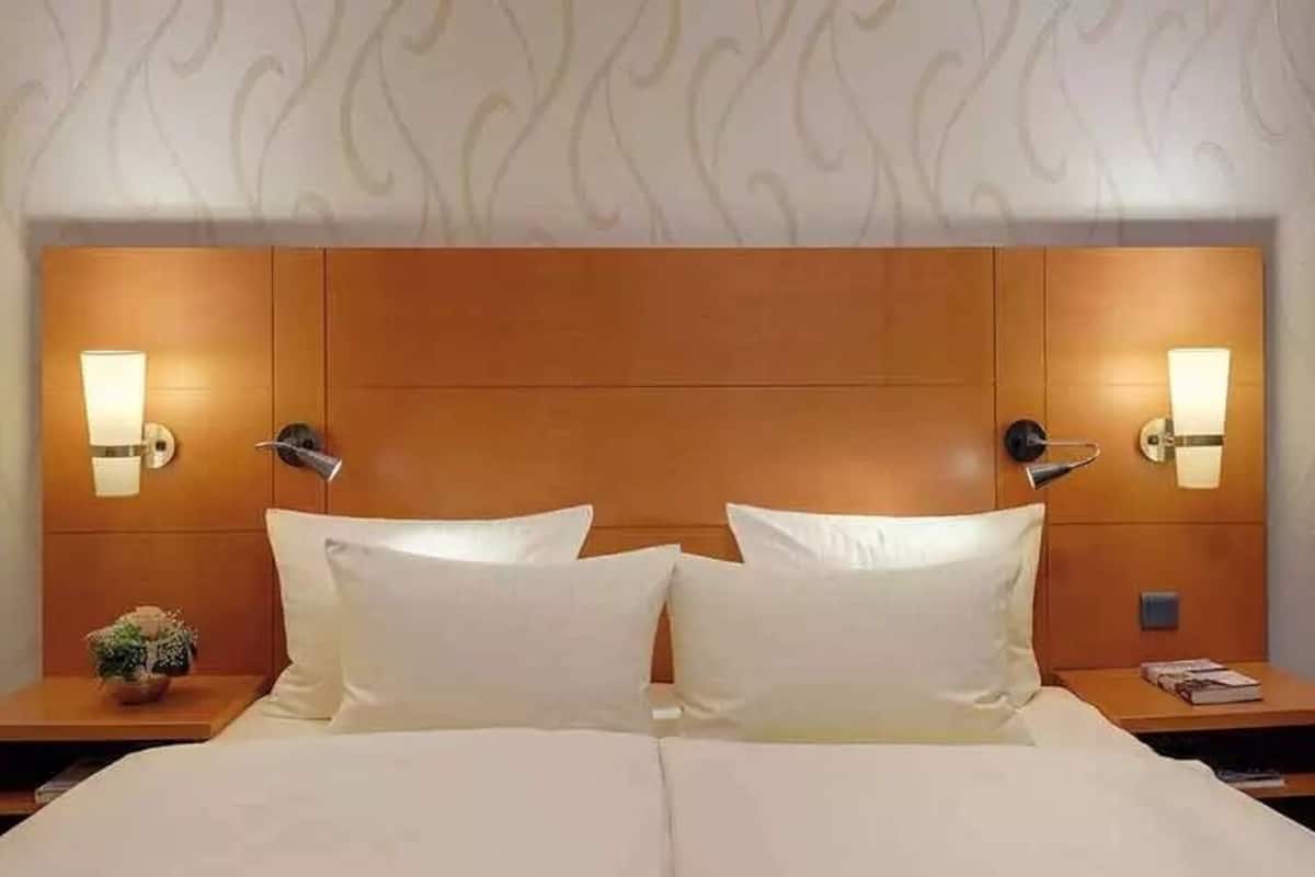 Une chambre d’hôtel avec un grand lit, deux tables de chevet et des lampes fixées au mur.