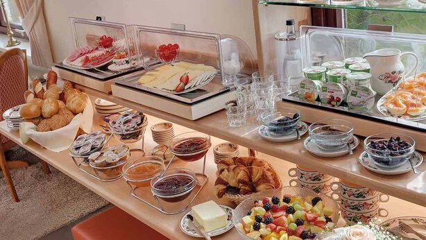 Ein Buffet mit verschiedenen Speisen, darunter Gebäck, Früchte und Milchprodukte.