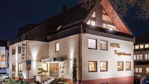 Ein Hotel mit modernem Design, das eine markante Fassade, zahlreiche Fenster und eine gut sichtbare Treppe zum Eingang zeigt.