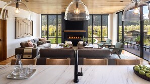 Una sala de estar moderna con chimenea, ventanas amplias y un comedor.