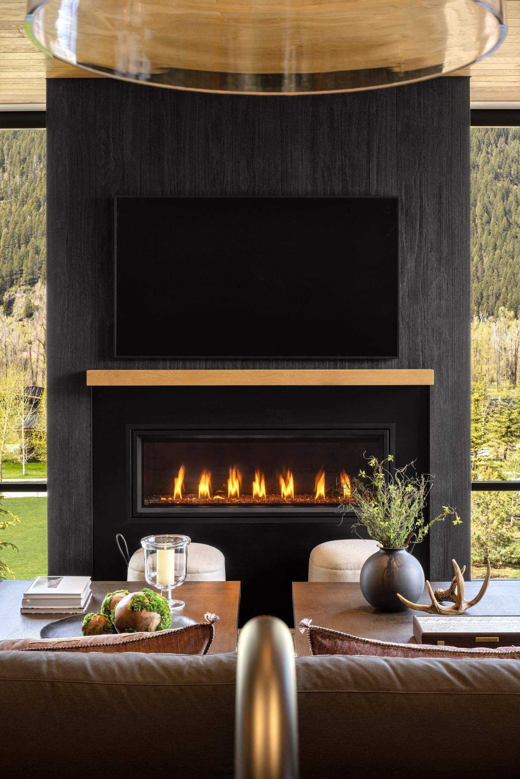 A modern fireplace with a flat-screen TV above it, set in a dark wood panel.