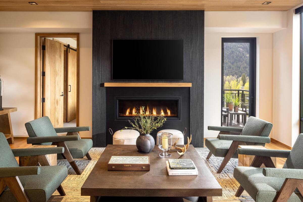 A modern living room with a fireplace, comfortable seating, and a large TV.