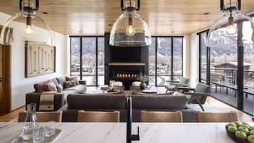A modern living room with a fireplace, large windows, and a dining area.